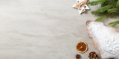 The concept of Christmas card. Homemade pastries, Christmas tree-shaped biscuits, spruce branches and decorations on a stone table. Top view.