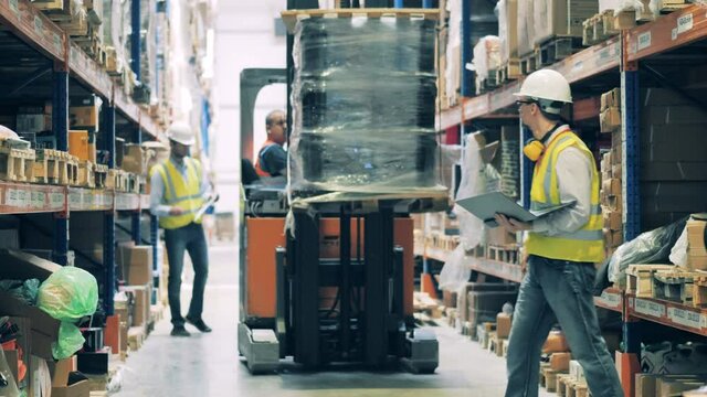 Warehouse worker on a forklift getting up goods to upper shelf