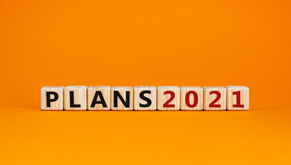 Business concept of planning 2021. Wooden cubes with the inscription 'Plans 2021'. Beautiful orange background, copy space.