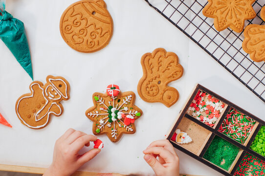 Kids hands decorating Christmas cookies with sprinkles