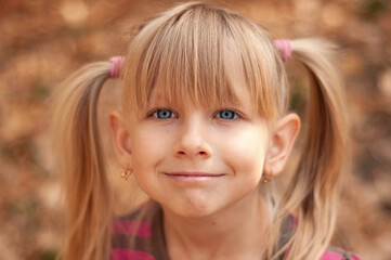 Fototapeta premium Portrait of a beautiful girl in the autumn park. Cute child with blond hair.