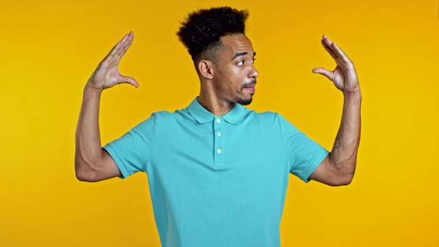 African american bored man showing bla-bla-bla gesture with hands and rolling eyes isolated on yellow background. Empty promises, blah concept. Lier