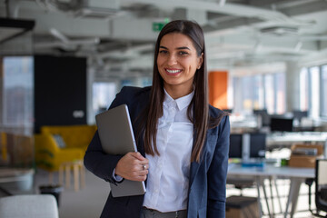 Portrait of the beautiful businesswoman holding a laptop in the office.