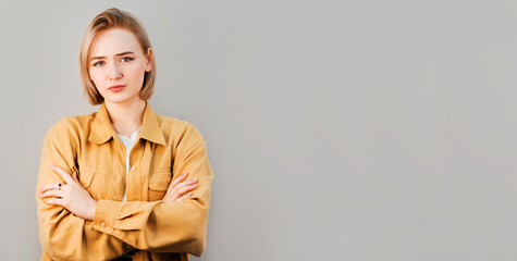 Portrait of a happy woman standing with arms folded isolated on a gray background