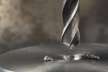 metal drill bit make holes in steel billet on industrial drilling machine. Metal work industry and...