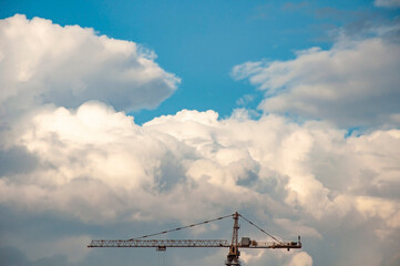 a tower crane against a blue sky with clouds.