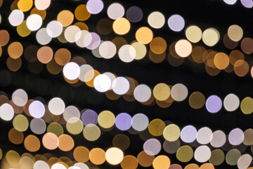 Light gold purple and blue Christmas light shiny abstract round bokeh on black background. Colourful Glitter bokeh from blurry decoration bulbs.