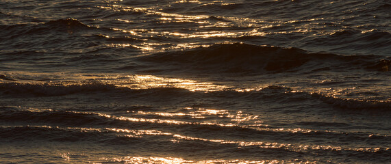 Warm colors of the sunset light reflectet on the water rippled surface of the ocean