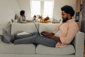 Obraz premium Black man with earphones sitting on the floor and using laptop