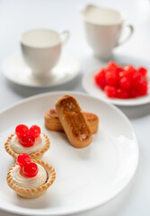 Selective focus . Dessert of cherry filled baskets with two almond fingers and sweet cherries.