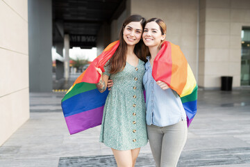 Two friends hugging with a rainbow gay flag