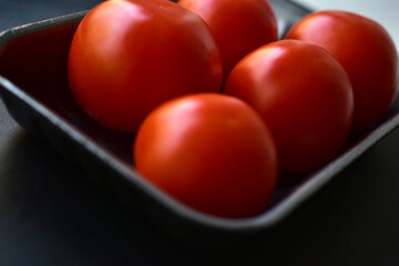 Red ripe tomatoes in a package on a black background