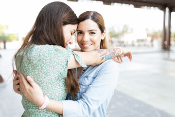 Blond young woman hugging her latin girlfriend