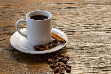 cup with coffee, cinnamon and coffee beans on rustic table