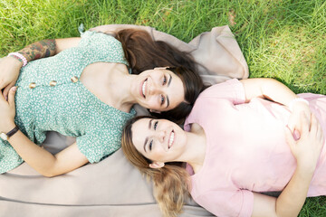 Young girlfriends lying on a blanket in the grass