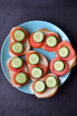 Sandwiches on a green plate with cucumber and tomato on white bread