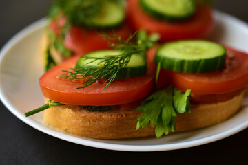 Diet sandwiches with greens, cucumber and tomato on a white plate