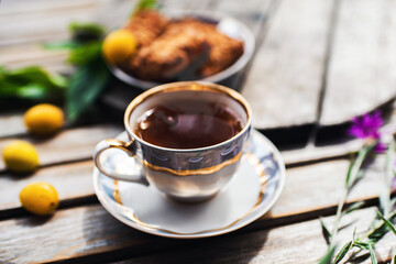 Cup of hot tea and cookies, bowl with yellow plums in   on a wooden table. Coziness and comfort in the house. Thanksgiving day.