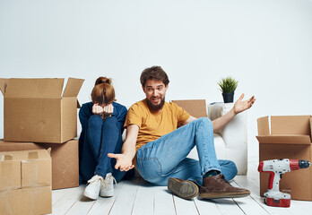 man and woman on the floors in a new apartment with boxes and tools for repair