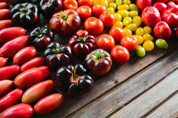 The harvest of vegetables. Different varieties of tomatoes
 are laid out on a wooden background....