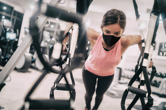 Woman Training At Gym Wearing Face Mask For Coronavirus Prevention While Exercising Strength Indoors.