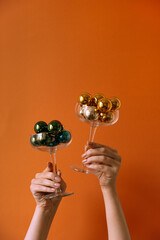 Female hands holding two wineglasses with Christmas baubles. Christmas / New Year concept.