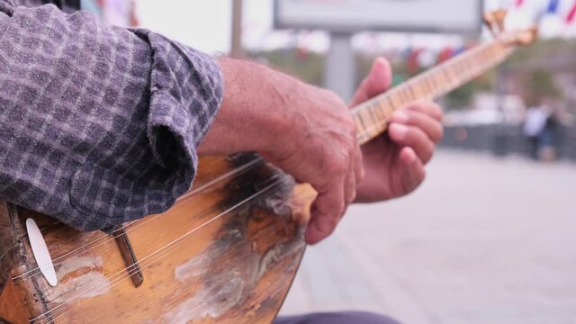 Playing baglama Turkish string music instrument. An old and worn-out music instrument