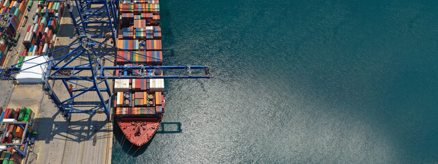 Aerial top down ultra wide photo of industrial cargo container ship loading in logistics terminal...