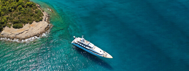 Aerial drone ultra wide photo of luxury yacht with wooden deck anchored in tropical exotic island bay wit turquoise sea
