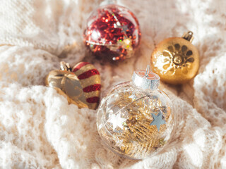 Decorative balls for Christmas tree on cable-knit sweater. Transparent sphere with red, golden spangles inside. Winter holiday spirit. New year celebration.