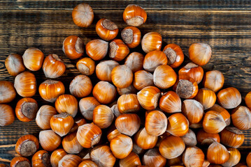 Hazelnuts on a pile close up. Texture of nuts on an old wooden board. Lots of nuts on a brown shabby table.