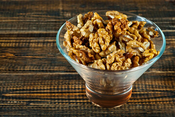 Peeled walnuts in a bowl. Nuts close up on an old wooden board. Food on a shabby table.