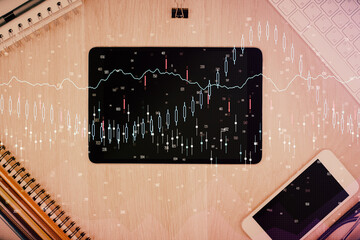 Double exposure of forex graph hologram over desktop with phone. Top view. Mobile trade platform concept.