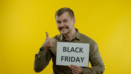 Cheerful handsome man smiling and showing Black Friday inscription, rejoicing good discounts, low prices for online shopping sales. Studio shot on yellow background