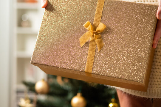 Hand Holding Christmas Gift Box In Front Of Holiday Lights