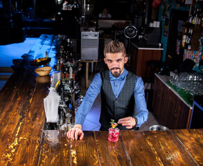 Focused barman decorates colorful concoction at bar