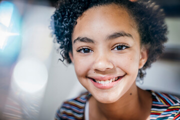 Pretty, smiling teen girl sitting on stairs in mixed rainbow light