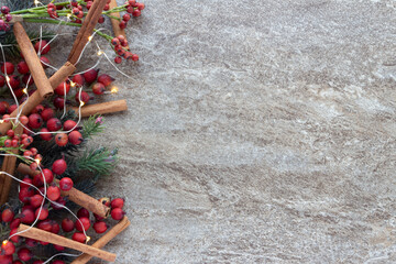 Horizontal  Christmas background, red berries, evergreens, cinnamon sticks and lights