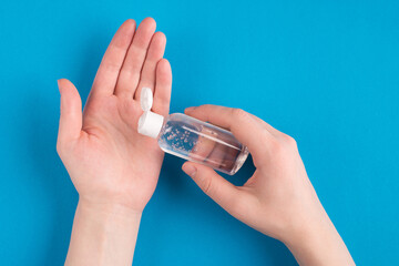 Close up photo first person view you of female hands applying using transparent medical sanitizing liquid from little bottle isolated over bright color blue background