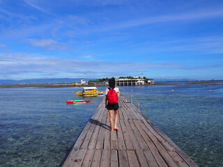 A long wooden bridge leading to the island and a woman standing on the bridge, Nalusuan Island, Cebu, Philippines