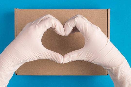 Safe delivery from post concept. Top above overhead close up first person view photo of hands making giving heart shape sign over cardboard box isolated over blue color background