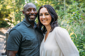 Portrait of happy mixed race couple hugging and smiling outside