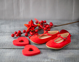 red baby shoes as decor and background on dark wood surface, Christmas decorations for newborns