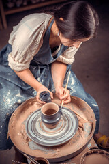 Master-ceramist creates a clay pot on a potter's wheel. Hands of potter close up. Ancient craft and pottery handmade work