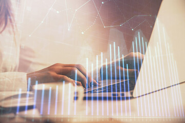 Double exposure of woman hands working on computer and forex graph hologram drawing. Financial...