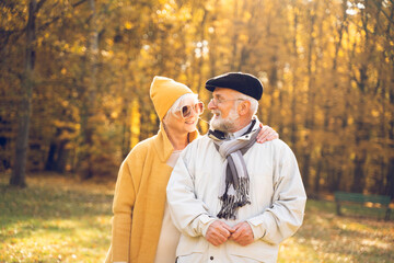 Happy senior couple walking and talking in beautiful autumn city park.