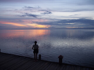 A woman stares at the beautiful reddish sky after sunset, Marine Sanctuary, Nalusuan Island, Cebu, Philippines