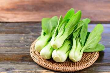 Fresh Bok Choy or Pak Choi(Chinese cabbage) on woven rattan plate with wooden background, Organic vegetables