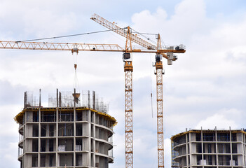 Tower cranes in action on blue sky background. Construction of new multi-storey buildings. Residential building is being constructed use of crane. Pouring of concrete in formwork