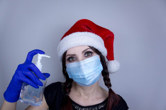 Woman wearing protection face mask against coronavirus. Woman in a mask and Christmas hat with sanitizer. Funny Christmas accessory. Medical mask, Close up shot, Select focus, Prevention from covid19